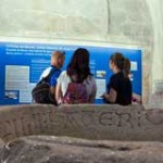 3 personas de espalda leyendo cartel de museo